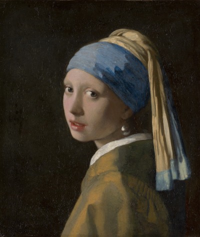 A young white woman wearing a large earring that catches the light turns toward the viewer and stares out. Her hair is tied up in a blue and yellow turban. She is pictured against total blackness.