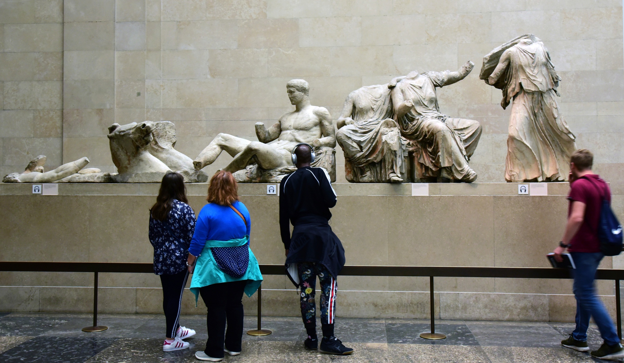Visitors stand in front of ancient marble sculptures in a museum
