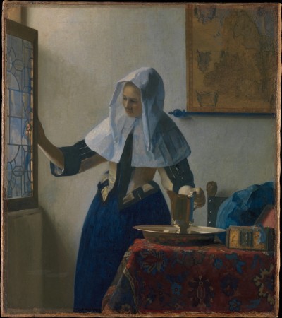 A white woman in a blue dress and a light blue hood holds a silver cup on a plate in one hand and a partially opened window in the other. The cup and plate are on a table covered in a red fabric; a pile of blue fabric sits to the site. A map hangs on the wall behind her.