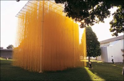 large-scale outdoor sculpture made of us hanging yellow threads suspended from a metal frame