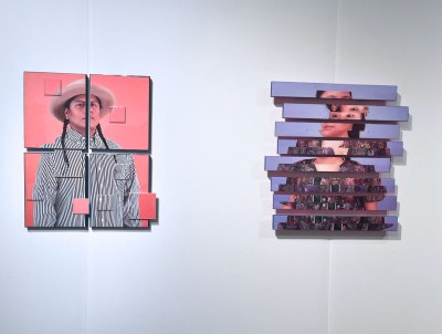 Two photo-based sculptures, showing fragmented portraits of two different people, hang on a wall.